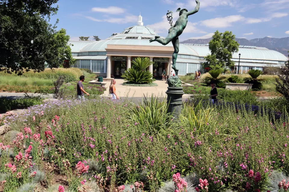 Glass-topped conservatory building with bronze statue in foreground at Los Angeles County Arboretum and Botanic Garden